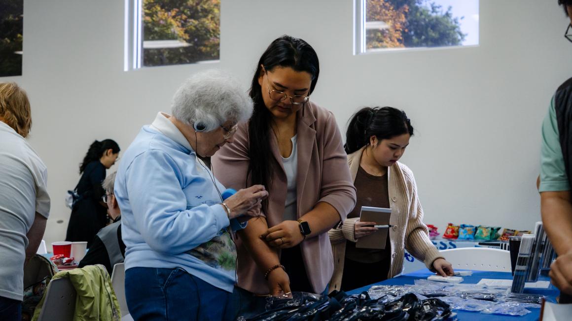 A VTA staff member assists a hearing-impaired attendee at a resource table during the Coffee with the Community event.