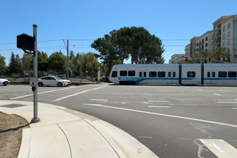 vehicle waiting at the light and VTA train on tracks