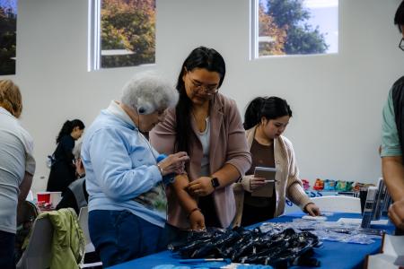 A VTA staff member assists a hearing-impaired attendee at a resource table during the Coffee with the Community event.