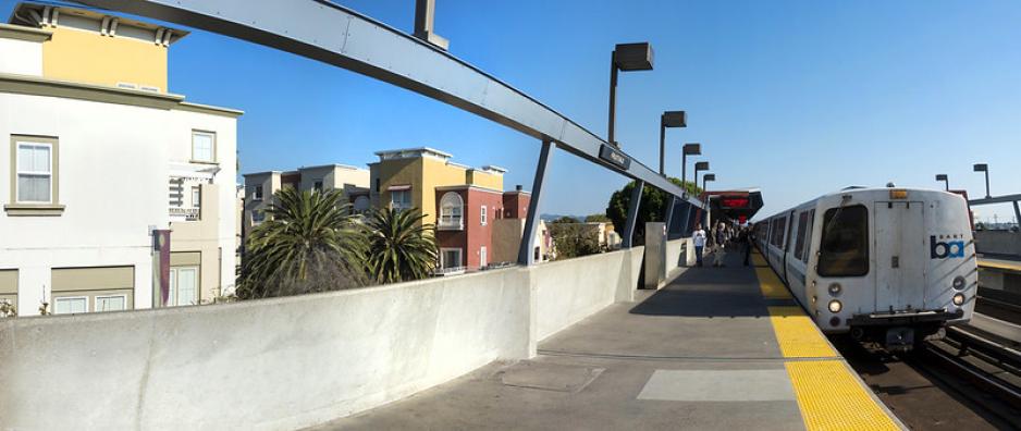 S2C6.5G3_FruitvaleBart-SPUR-SergioRuiz.jpg A photo of BART at an elevated station next to apartment buildings.