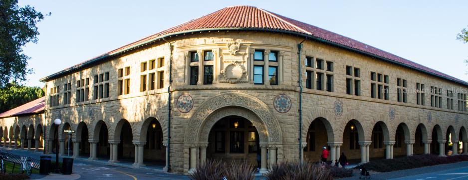 Photo of older brown stone building with red roof and ornate archways