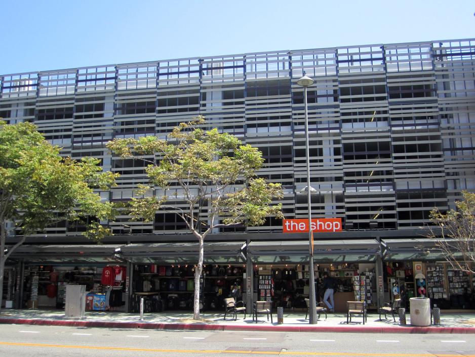 Photo of a parking structure covered in decorative metal with shops on the bottom floor